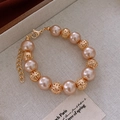 Dettaglio del bracciale con perle champagne, sfere dorate traforate e chiusura su lino - Bracciale - Oro