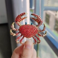 Macro shot of luxury red rhinestone crab brooch with gold plating and blue eyes - Red