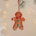Lebkuchenmann-Anhänger mit roter Schleife, 10 cm hoch, hängend an einem Weihnachtsbaumzweig - Fliege Lebkuchenmann