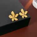 Macro shot of gold flower earrings with metallic texture on a black jewelry box - Earrings - Gold