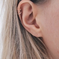 Close-up of minimalist stainless steel hoop earrings and a tiny gold ball stud on the ear - Steel
