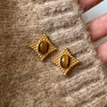 Detail of vintage tiger eye stone earring with starburst frame on brown knit fabric - Gold-Tiger's Eye