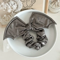 Detail of metallic grey bat wing bow hair scrunchie on a white ceramic display plate - Grey Large Bat