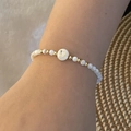 Close-up of white beaded bracelet with golden letter D bead worn on a female wrist - Letter D Style (D)
