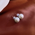Dettaglio dell'orecchino di perle bianche tonde su sfondo di tessuto di raso marrone - 12mm Perla Grigia (Perno d'Argento)