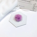 Close-up of a soft purple mink fur pompom on a decorative white hexagonal tile - Purple