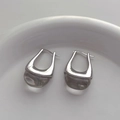 Detailopname van zilveren U-oorbellen met heldere druppelhangers op wit plateau - Zilver