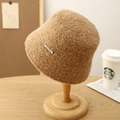 Detalle de la textura del gorro de lana marrón con emblema metálico en soporte - Camel