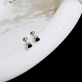 Detailed close-up of heart-shaped black zircon stud earrings with screw ball backings - Heart / Steel