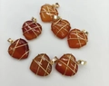 Detailed shot of seven wire-wrapped heart pendants made of carnelian stones with gold finish - Natural Red Agate