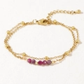 Detailed shot of double-layered gold bracelet with pink gemstones and lobster clasp - Pink/Ruby Red