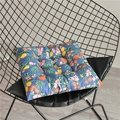 Detailed view of a thick floral chair cushion with ties on a black metal chair frame - 40x40cm / Blue Lemon