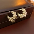 Macro shot of gold plated C-shaped earrings with twisted geometric layers on leather - Real Gold Plated (Gold) / Gold