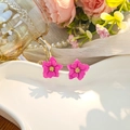 Macro shot of rose pink floral stud earrings on a white tray with petal details - Pink