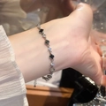Primer plano de una pulsera dorada con tréboles negros y circonitas en muñeca femenina - 5# Pulsera Trébol Negro (Chapado en Oro Real)