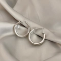 Polierte silberne Creolen auf elegantem beigefarbenem Seidenstoff als Detailansicht - Silber