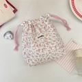 Close-up of floral drawstring storage pouch with pink cotton rope and woven brand label - Pink