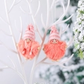 Pink knitted Christmas angel ornaments with wooden faces and fuzzy bodies hanging on a branch - Cloak Boy and Girl Set / Orange Pink