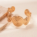 Detailed view of the gold spiral texture on a metallic open cuff bracelet - Gold