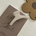 Vista dettagliata di una grande pinza per capelli bianco perlato traslucido dal design curvo - Pinza a Gruccia ad Arco con Etichetta Oro