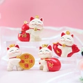 Set di quattro gatti della fortuna in resina bianca e rossa su sfondo rosa moderno - Collezione di gatti portafortuna