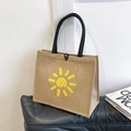 Linen tote bag in brown with yellow sun pattern and black handles on a sofa - Sunshine