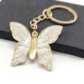Macro shot of gradient butterfly keychain with golden metal frame and glitter details - White