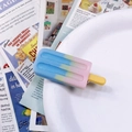 Close-up of a gradient popsicle hair clip with a gold metal base on a white bowl - Pink-Blue Gradient Popsicle Hair Clip