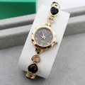 Detailed macro of gold heart charm bracelet watch with crystal accents and grey dial - Rose Gold + Black