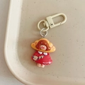 Close-up of cute cartoon girl keychain with red dress and croissant hairband in a tray - Croissant Girl