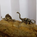 Pair of vintage copper dinosaur figurines on a rock base for home decoration - Diplodocus