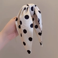 Elegant beige silk polka dot bow hair claw clip with a ribbon knot held in hand - Off-white with Black Polka Dots