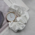 Close-up of white silk scrunchie watch strap with golden case on a magazine - White