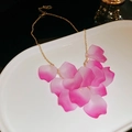 Detalle del collar de borlas con pétalos de flores en degradado rosa sobre bandeja - Rosa