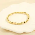 Close-up of golden beaded stretch bracelet with polished and faceted beads on shell tray - BR1683-C/Gold Polished Faceted Style