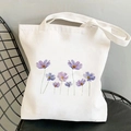 Weiße Canvas-Tragetasche mit lila Blumenillustration auf einem schwarzen Metallstuhl - Lila Blumen Illustration