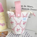 Detailed view of a quilted floral pencil pouch with a pink bow pattern and pink handle. - Pink