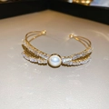 Bracelet nœud doré élégant avec perle centrale et accents de zircone rectangulaires - Style Nœud et Perle Doré