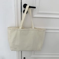 Detail of a beige large capacity canvas tote bag hanging on a white wooden door handle - Solid Beige (Beige Strap)