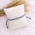 Detail of bohemian hand-woven beaded bracelet with blue string on white display cushion - Dark Blue