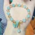 Hand beaded bracelet featuring light blue and amber crystals with butterfly pendant - Lake Blue