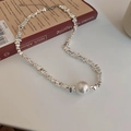 Macro shot of silver irregular beads and a large white pearl on a book surface - Necklace - Silver