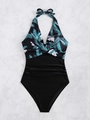 Detail view of slimming tummy control shirring and tropical floral print on the swimsuit - Black with Leaf Print