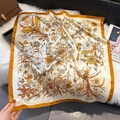 Detail of floral and butterfly print on ginger square scarf over a plush white surface - Orange
