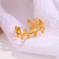 Minimalistischer verstellbarer Olivenblatt-Ring aus vergoldetem Edelstahl auf weißem Stoff - Einstellbar Offen / Blatt Stil / Gold