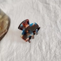 Tortoise shell hair claw clip with brown and teal acetate texture on white fabric - Black Blue Floral