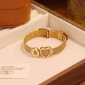Détail du bracelet en maille dorée avec breloques cœur et zéro dans un écrin à bijoux - Lettre O