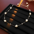 Detail of baroque pearls on a gold plated chain displayed on a black textured tray - Gold Beige Necklace (Gold Plated)