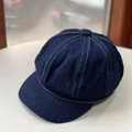 Classic dark blue denim newsboy cap with white contrast stitching on a minimalist surface - One Size / Dark Blue