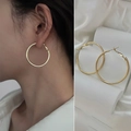 Eleganti orecchini a cerchio dorati mostrati in una vista laterale minimalista sul modello - Medio / Oro